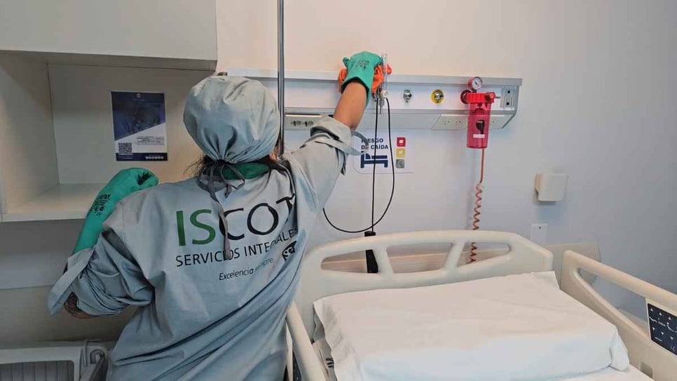 Colaboradora de ISCOT limpiando el panel de cabecera de una habitación en la Clínica Universitaria Reina Fabiola