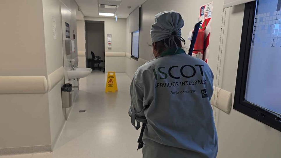 Colaboradora de ISCOT en un pasillo de internación con señalización de piso húmedo